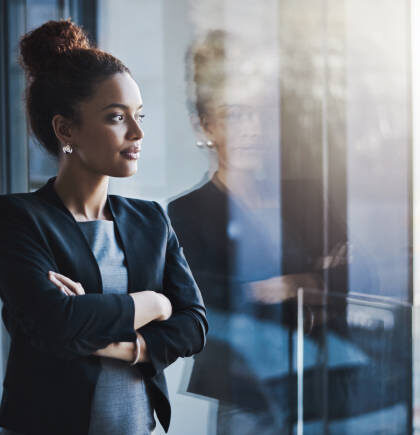 Shot of a young businesswoman looking out the window in an office
