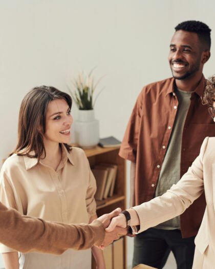 Two people shaking hands with two people standing in background