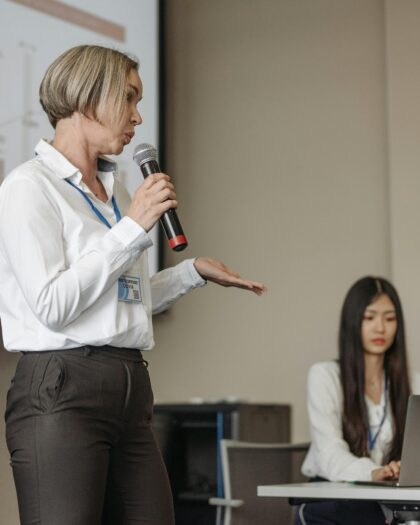 person lecturing while person takes notes in the background