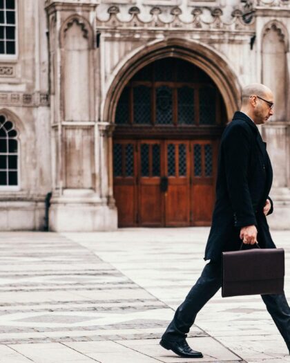 Business man walking through elegant stone plaza with medieval stone building in background