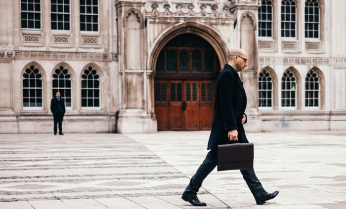 Business man walking through elegant stone plaza with medieval stone building in background