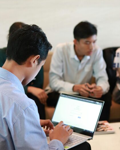 Over the shoulder of man in business attire looking at his laptop screen (blurred)
