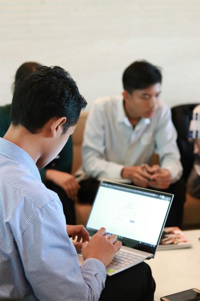 Over the shoulder of man in business attire looking at his laptop screen (blurred)