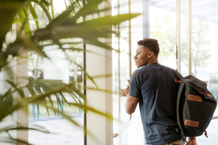 College student with backpack going through door