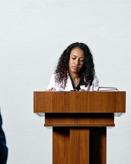Woman at podium in business attire giving speech in lecture hall