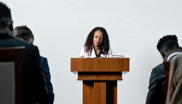 Woman at podium in business attire giving speech in lecture hall
