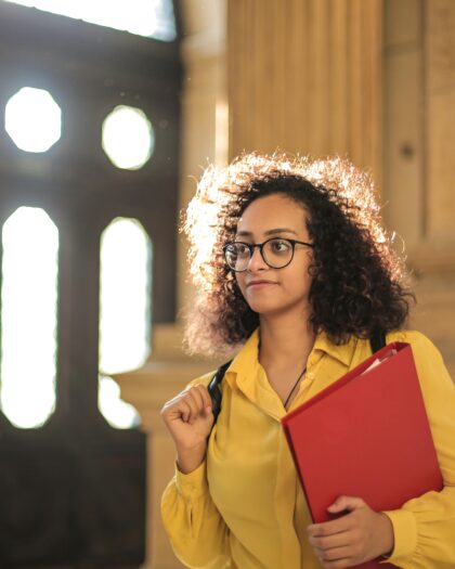 Student in yellow shirt carrying red binder