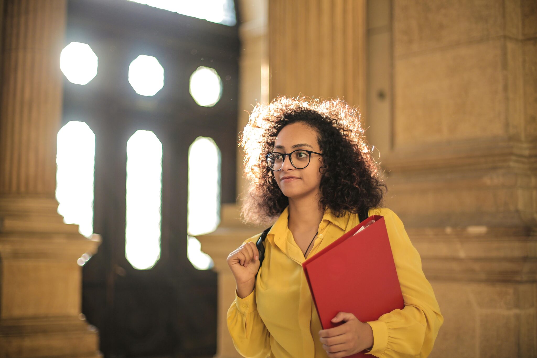 Student in yellow shirt carrying red binder