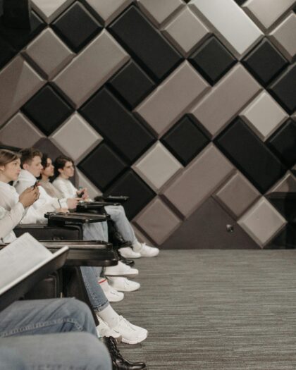 Group of students in business attire watching other student in business attire give lecture