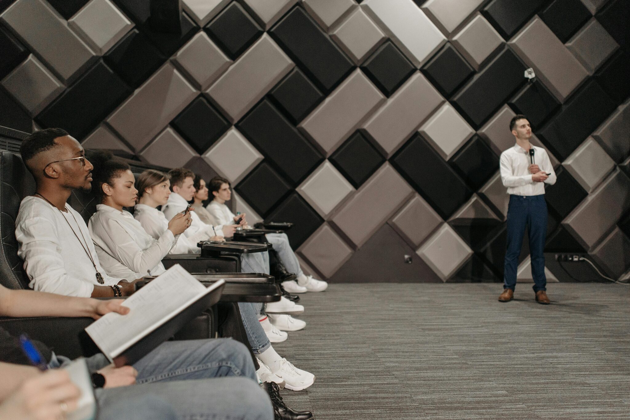Group of students in business attire watching other student in business attire give lecture
