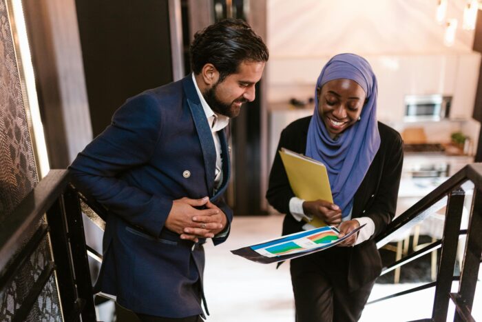 Woman and man in business attire on stairs looking at document with colorful graphs
