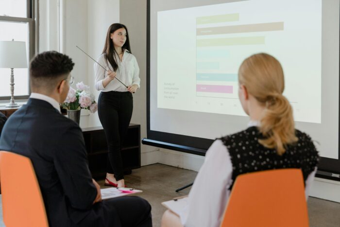 Woman in business attire giving presentation to two other people in business attire
