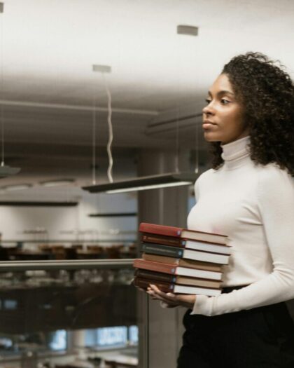 Student carrying small stack of books in library