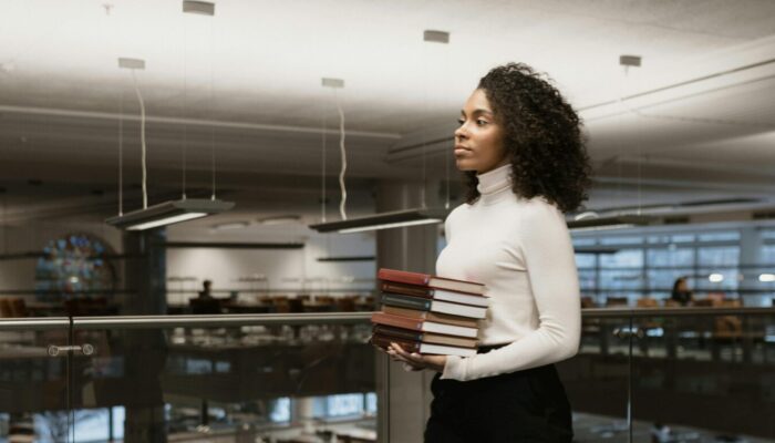 Student carrying small stack of books in library