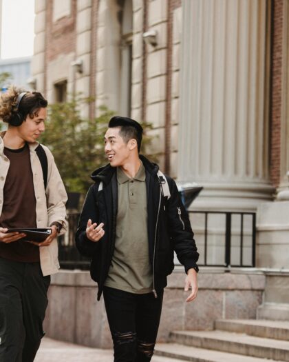 Two students walking next to greek-style pillars