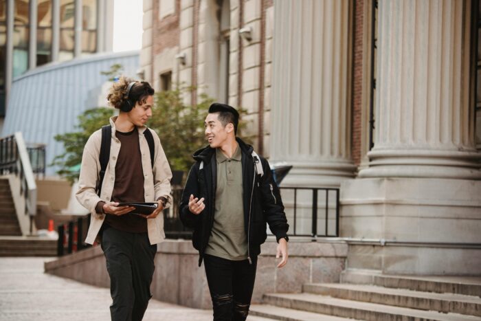 Two students walking next to greek-style pillars