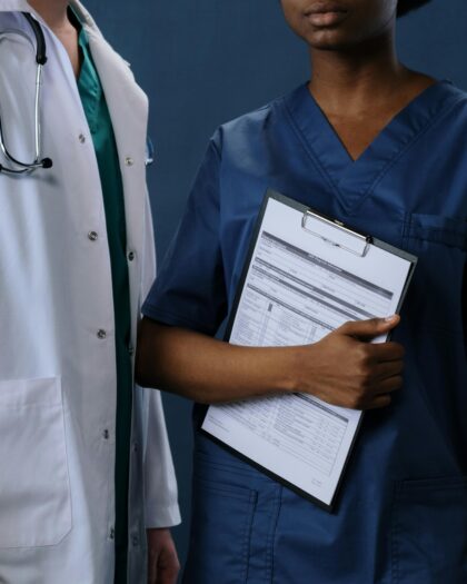 Photo of Male doctor and female nurse holding a file, looking at the camera.