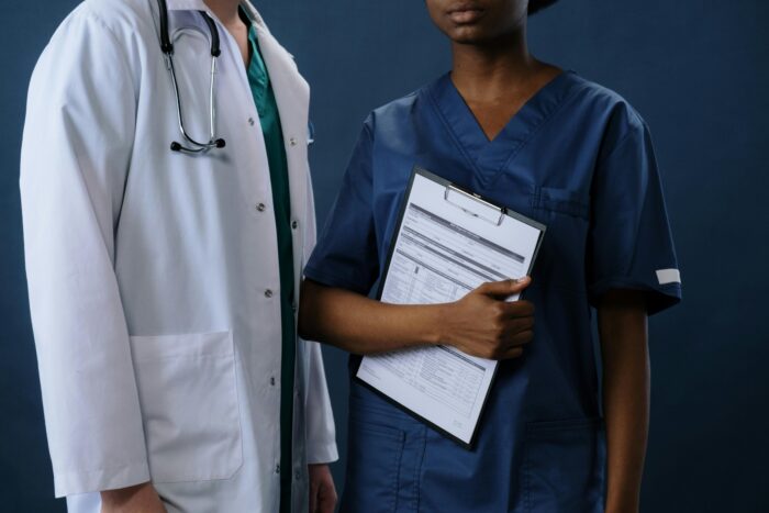 Photo of Male doctor and female nurse holding a file, looking at the camera.