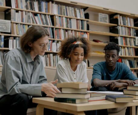 Three college aged students studying in library
