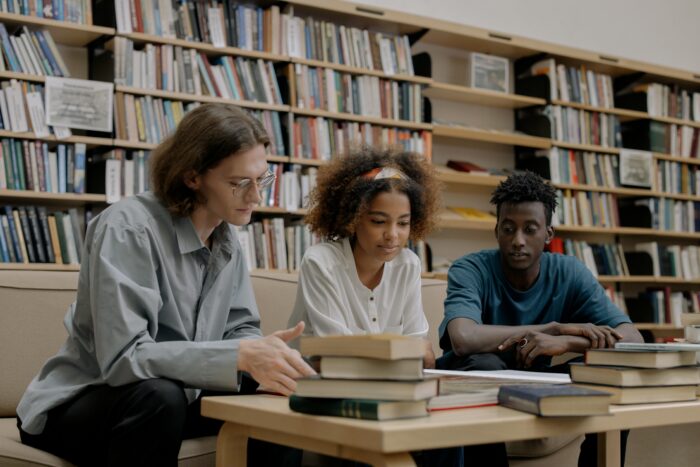 Three college aged students studying in library