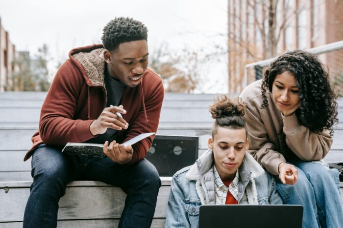 Three college students studying on campus stairs