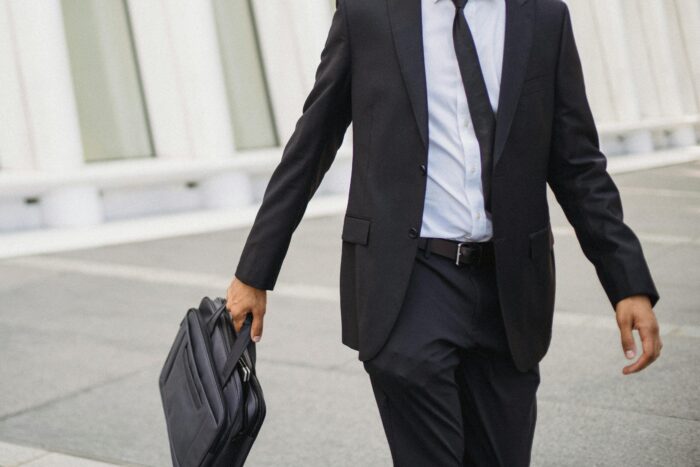 Image of torso of business man holding suitcase while walking outside