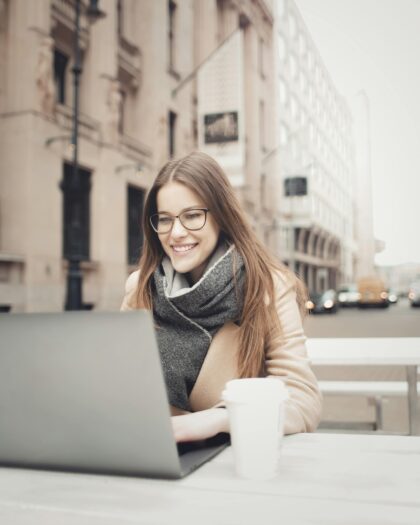 Woman sitting at outdoor table in Milan working on laptop next to a coffee