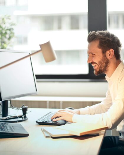 Man in business attire sitting at desk looking at computer screen