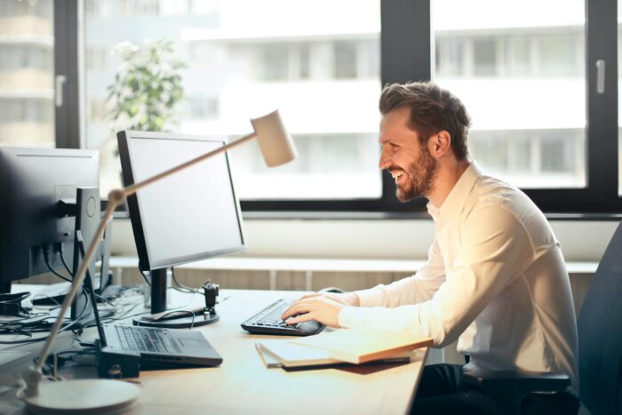 Man in business attire sitting at desk looking at computer screen