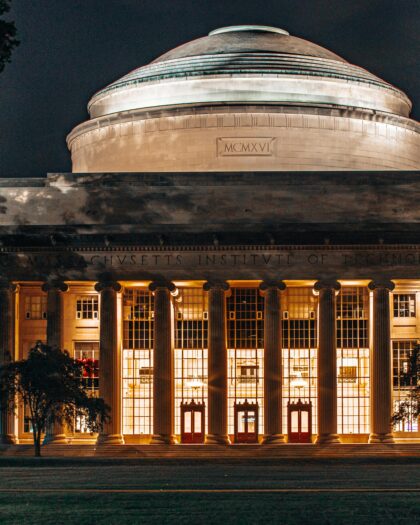Grand greek-style building with pillars and dome on top with "Massachusetts Institute of Technology" inscribed across the stone molding