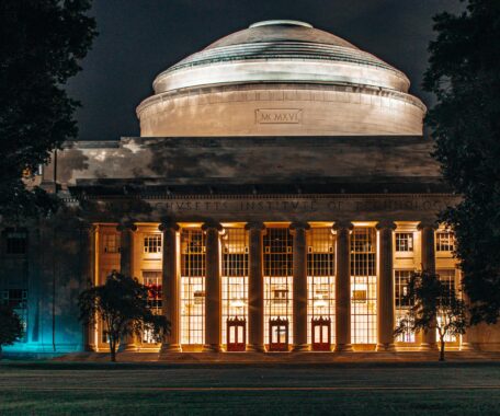 Grand greek-style building with pillars and dome on top with "Massachusetts Institute of Technology" inscribed across the stone molding