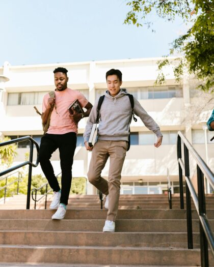 Three college-age boys walking down campus stairs