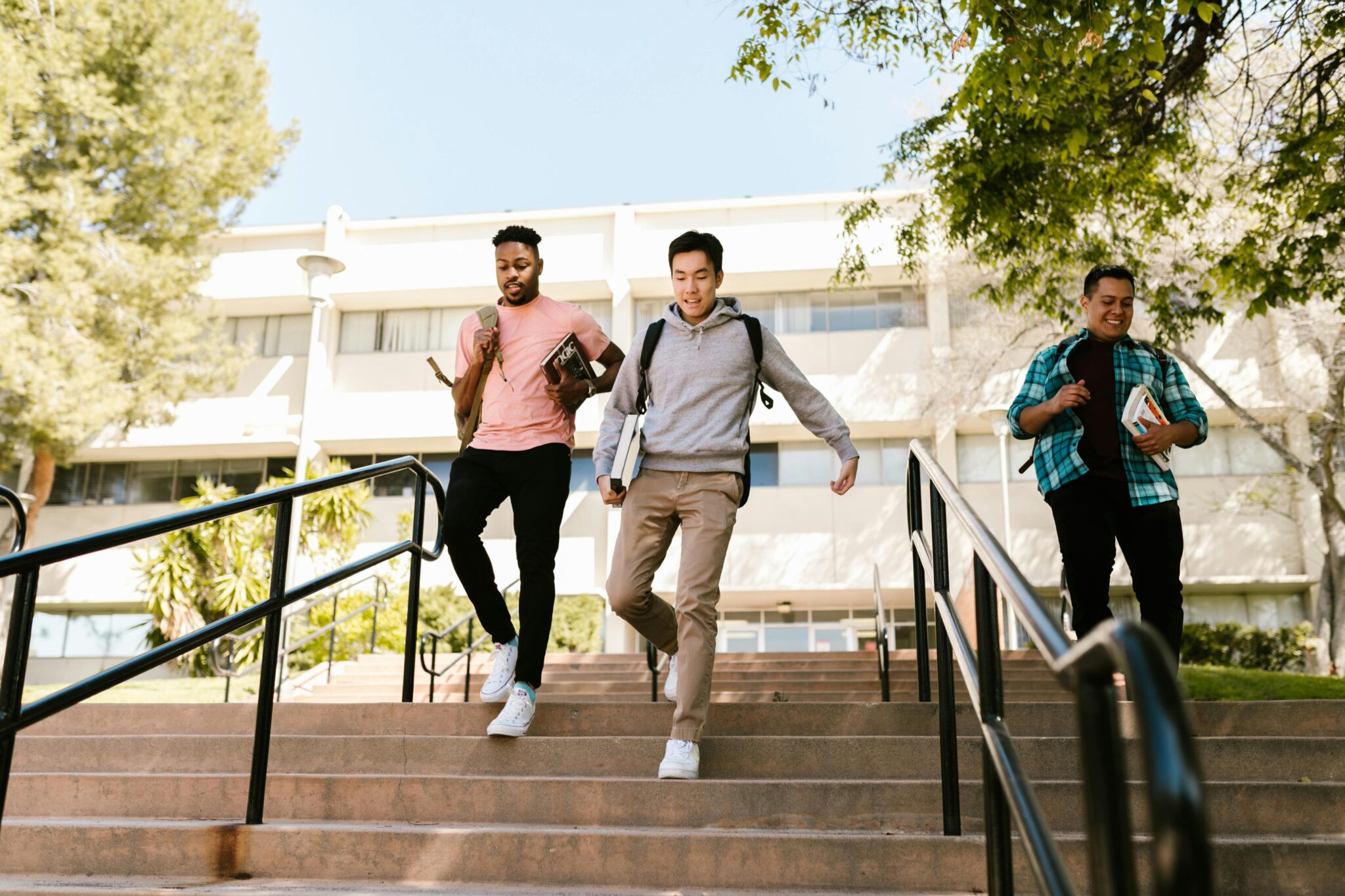 Three college-age boys walking down campus stairs