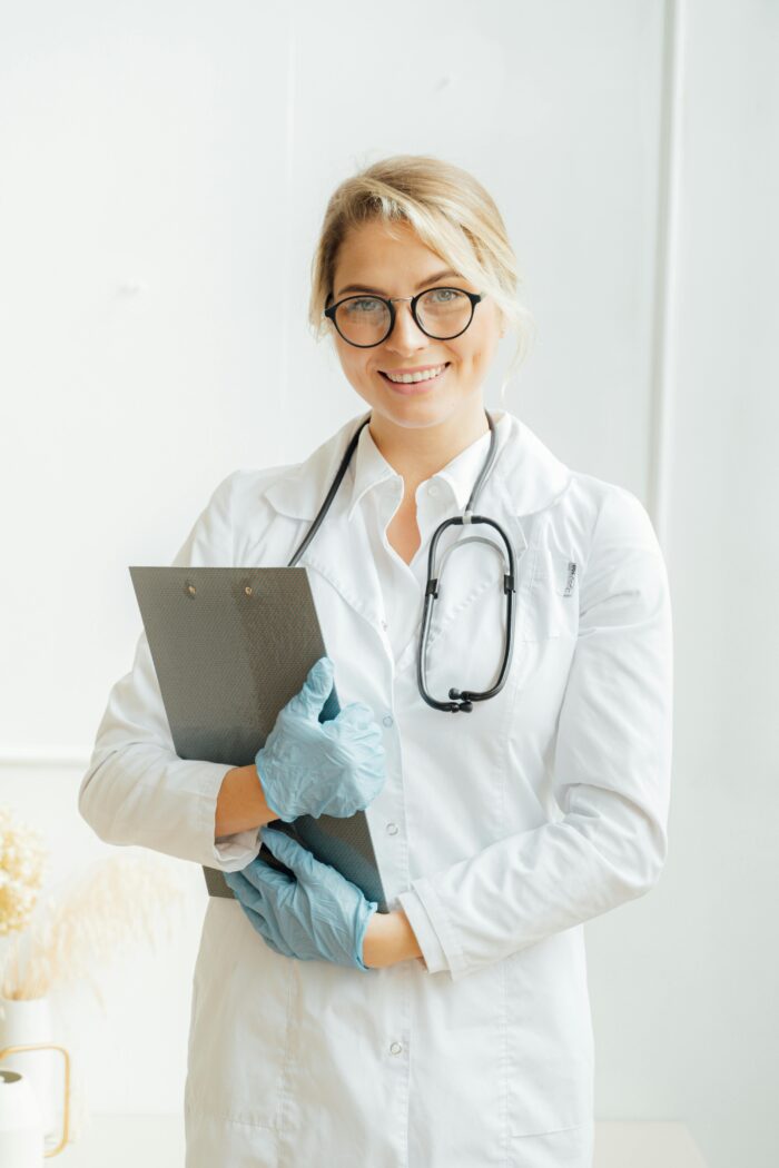 A photo of female Doctor holding a stethoscope and file looking towards the camera