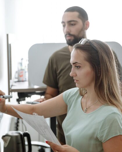3 students using a white board intently