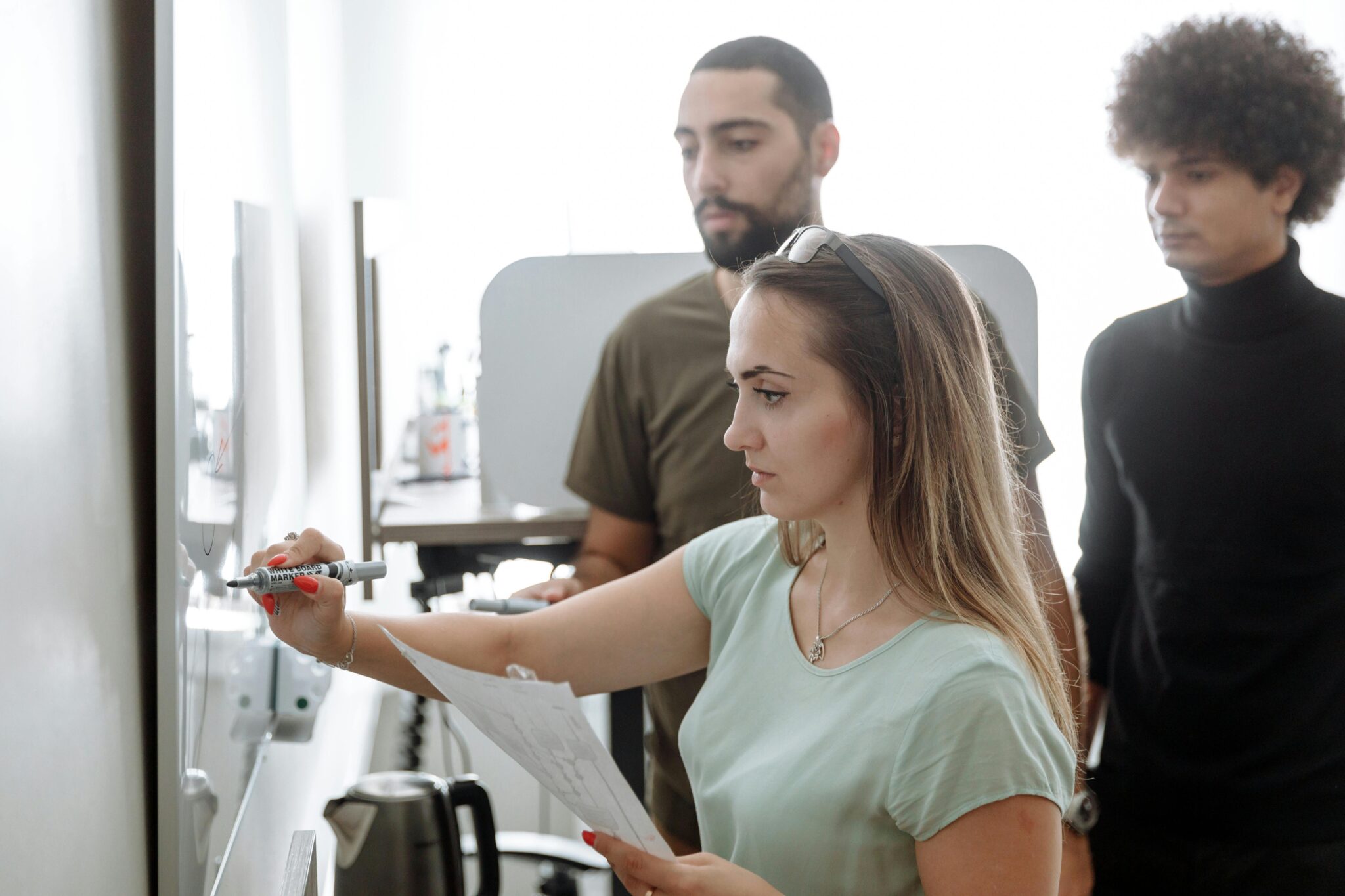 3 students using a white board intently