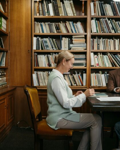 Two students and professor sitting at wooden library table