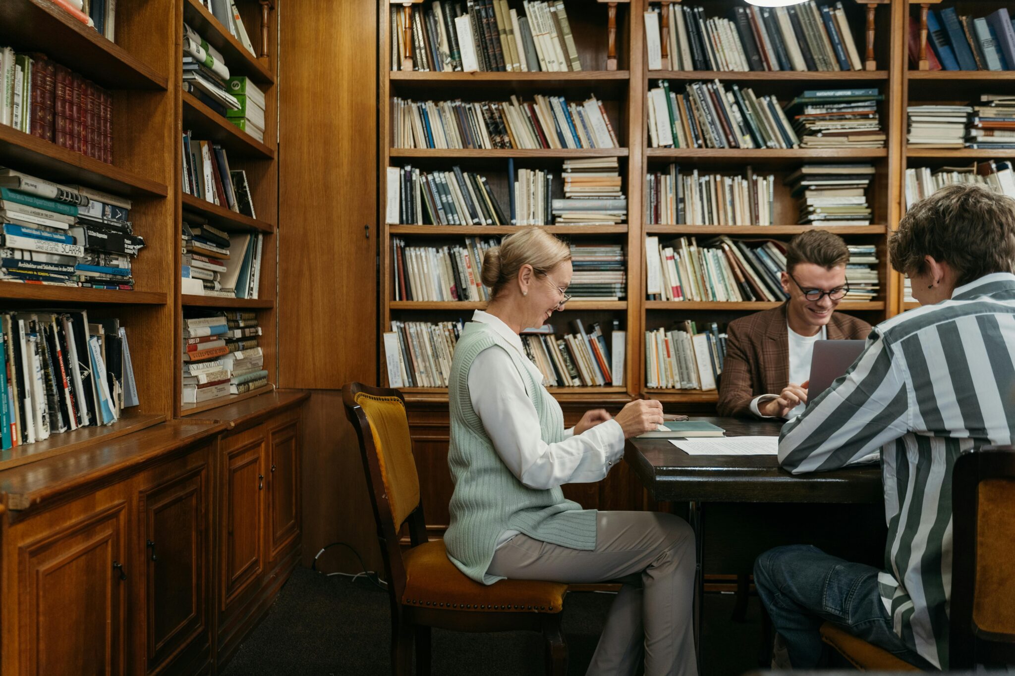 Two students and professor sitting at wooden library table