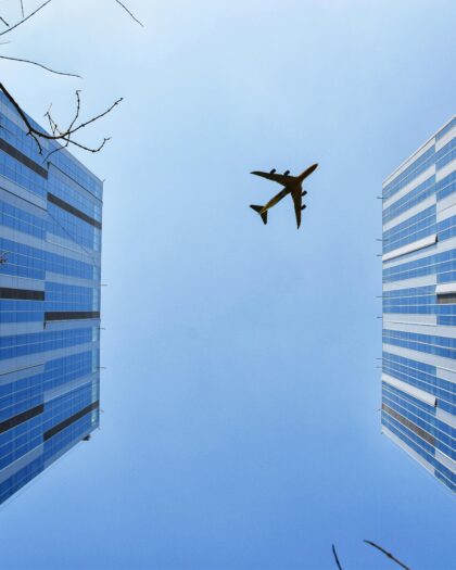 View of skyscrapers from the bottom, with airplane in sky