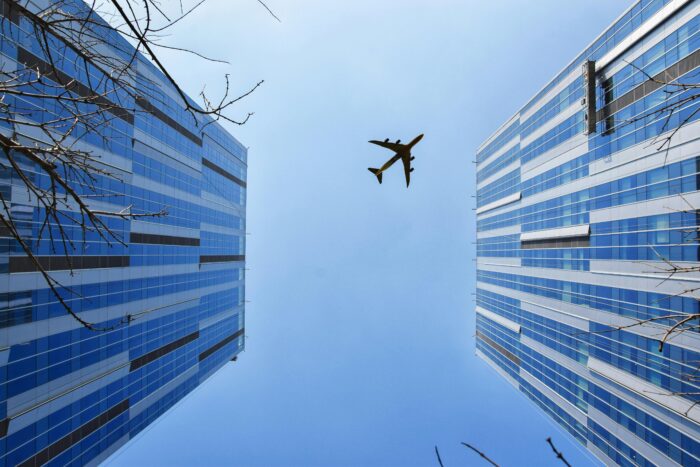 View of skyscrapers from the bottom, with airplane in sky