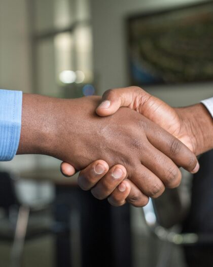Handshake between two arms wearing button up shirt sleeves