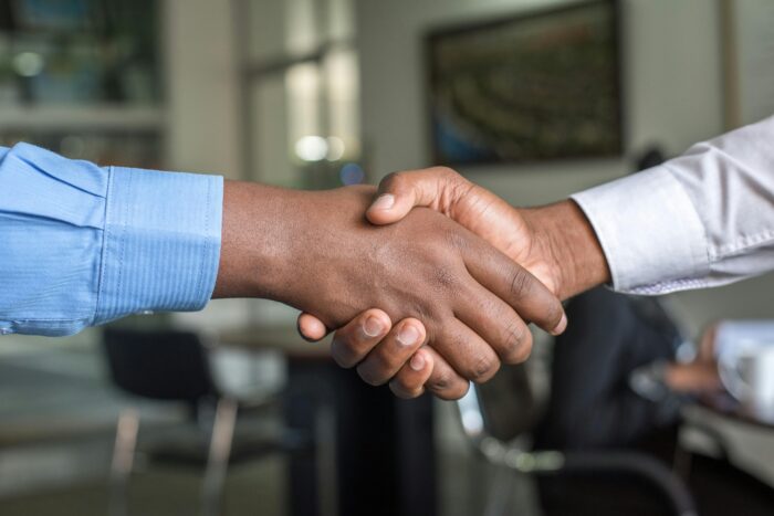 Handshake between two arms wearing button up shirt sleeves