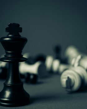 Black and white chess pieces scattered on black background