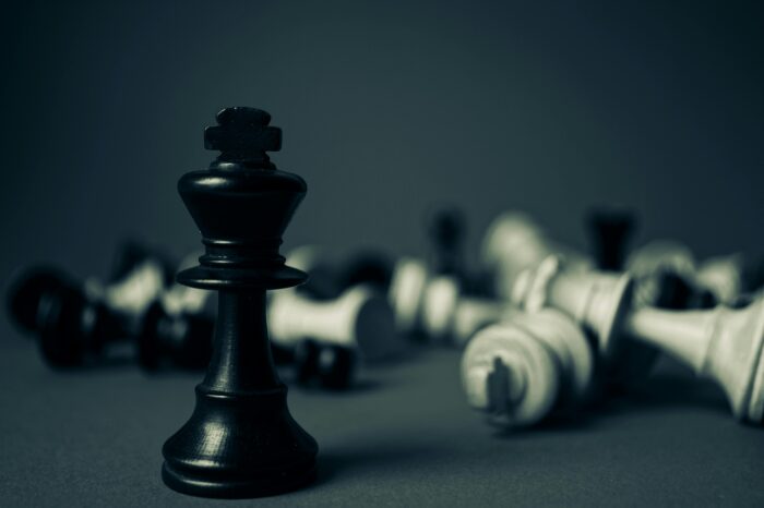 Black and white chess pieces scattered on black background