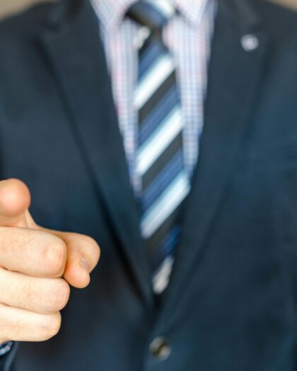 Torso of man wearing business suit pointing his finger to camera