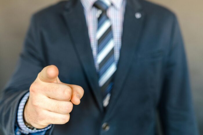 Torso of man wearing business suit pointing his finger to camera