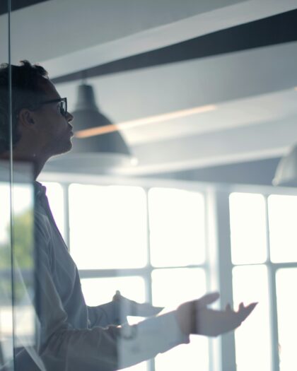 Man behind glass in business casual attire talking to someone off camera