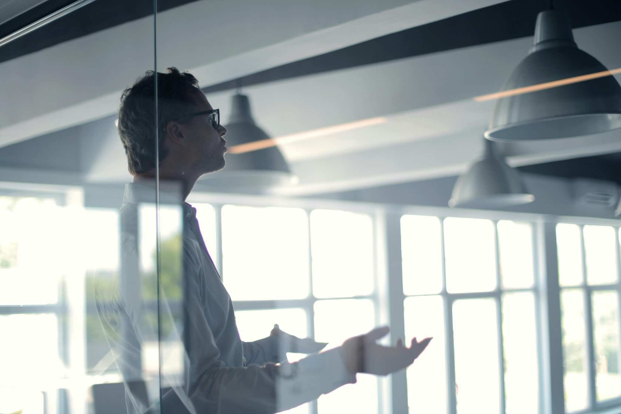 Man behind glass in business casual attire talking to someone off camera