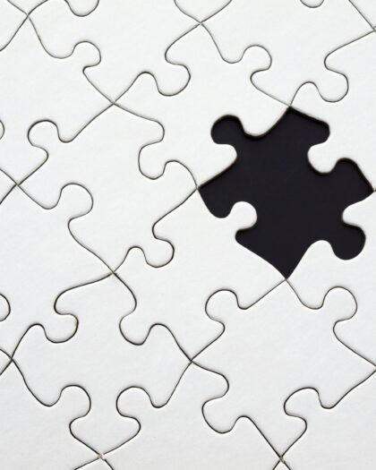 White puzzle pieces with a black space where there is a piece missing