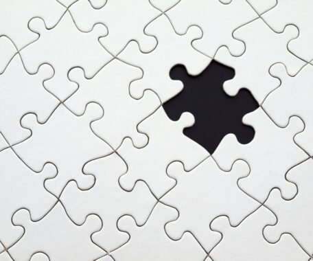 White puzzle pieces with a black space where there is a piece missing